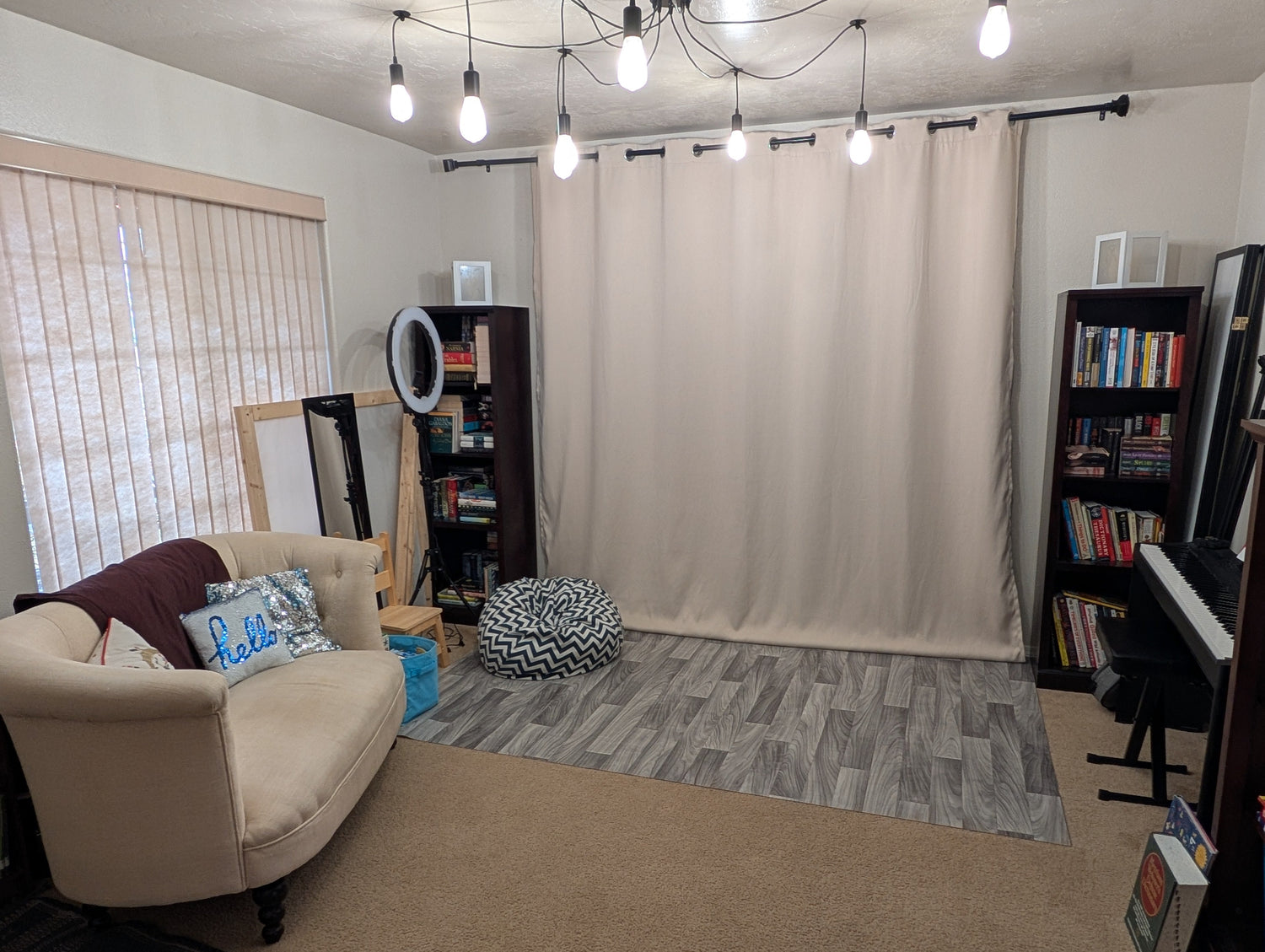 Photo Studio with beige sofa, bookshelves, and a curtain.